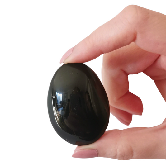oval shaped polished Black Tourmaline palm crystal held by hand