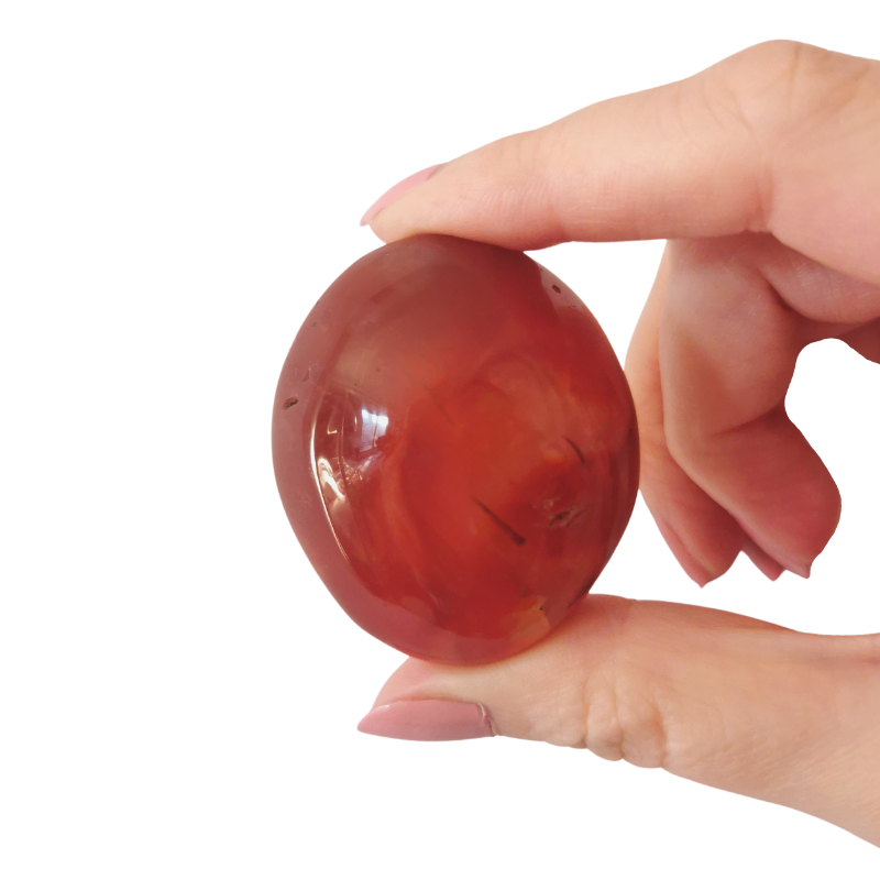 large tumbled fiery orange Carnelian palm crystal held by hand