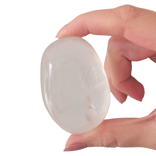 oval polished sheer with inclusions and rainbows within Optical Calcite palm crystal held by hand