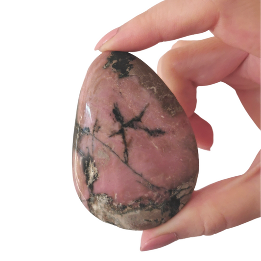 large polished pink and black Rhodonite palm crystal held by hand