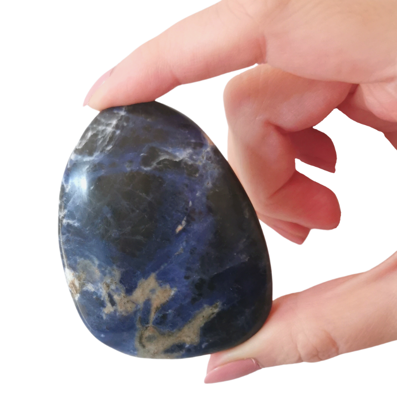 large rounded polished blue, black and white Sodalite palm crystal held by hand
