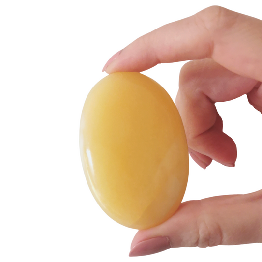 high quality oval polished Yellow Calcite palm crystal held by hand